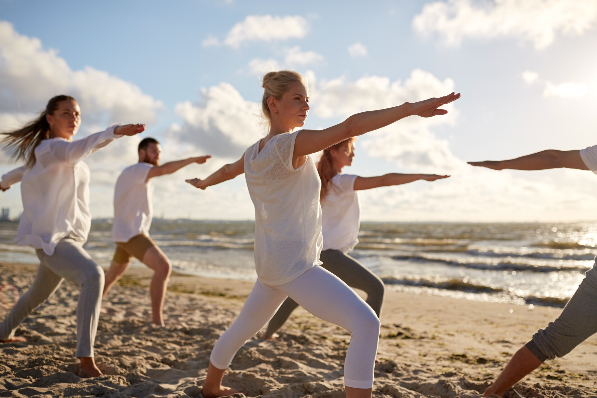Group of people making yoga exercises on beach