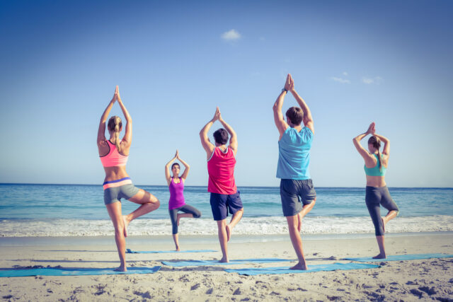 Friends doing yoga together with their teacher